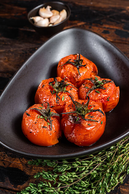 蔬菜烤箱烤樱桃西红柿配百里香和大蒜在盘子里托盘草药顶视图