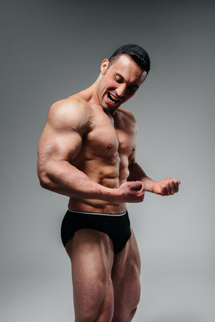 男子一个年轻的健美运动员赤裸上身在摄影棚里摆姿势 炫耀他的腹肌和肌肉运动梯度运动员年轻