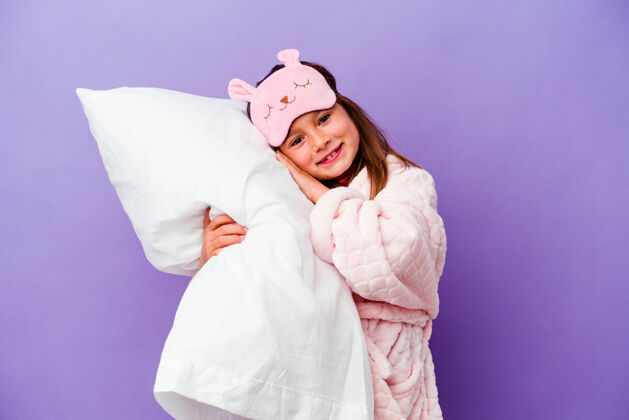 卧室小女孩抱着一个枕头快乐地孤立在紫色上结合微笑休闲
