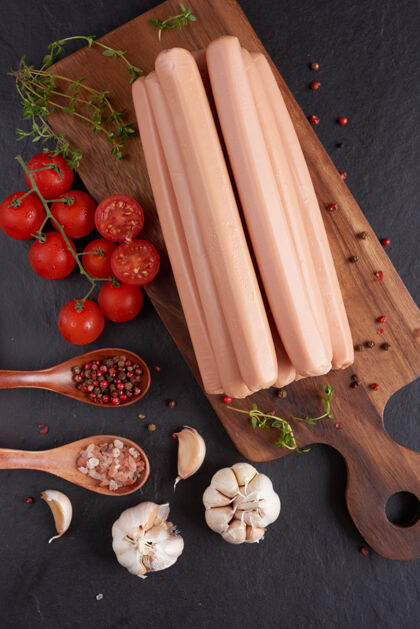 板经典的煮肉猪肉香肠放在砧板上 配胡椒和罗勒 欧芹 百里香和樱桃番茄膳食烹饪美味