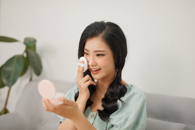 韩国人年轻微笑的亚洲女人在她的脸上垫垫子的肖像肖像美女粉底
