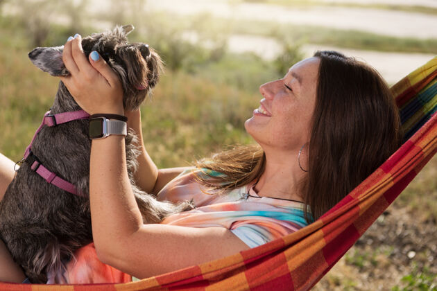 女人快乐女孩在野餐时躺在吊床上抱着一只小狗 生活方式 观念沟通放松女