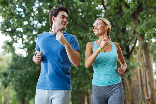 免疫力户外活动一对健康的情侣微笑着一起在树林里慢跑女性男性女人