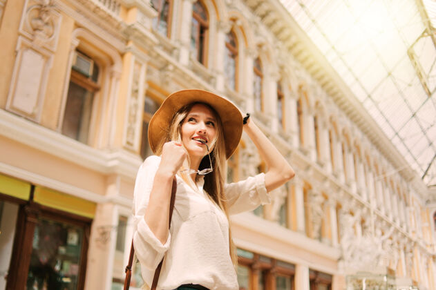 活跃一个年轻的金发女游客戴着帽子的城市建筑肖像探索微笑放松