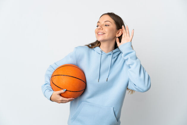 球员立陶宛年轻女子在白色背景下孤立地打篮球 手放在耳朵上听东西人成人运动