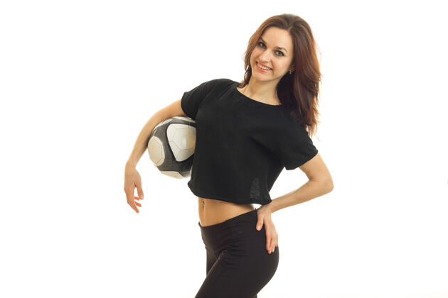 举行美丽开朗的女人微笑着 手里拿着足球 孤零零地站在白墙上足球人成人
