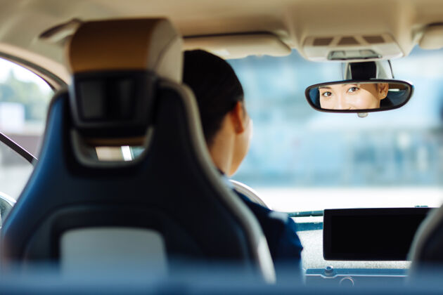 人专业司机坐在方向盘后面看着后视镜的可爱女人车辆汽车成人