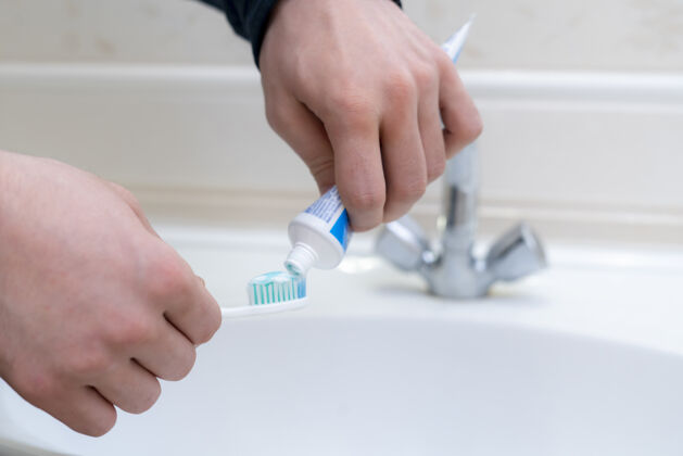 水平人挤牙膏的牙刷在浴室里白种人室内口腔