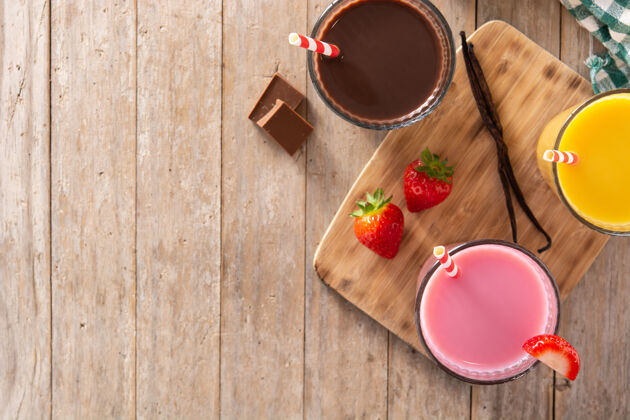 早餐巧克力 草莓和香草奶昔放在乡村木桌上稻草草莓美味