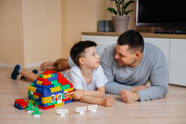 积木一个小男孩和他的父亲一起被一个建造师扮演 建造了一座房子建造了一个家庭的家多彩游戏室颜色