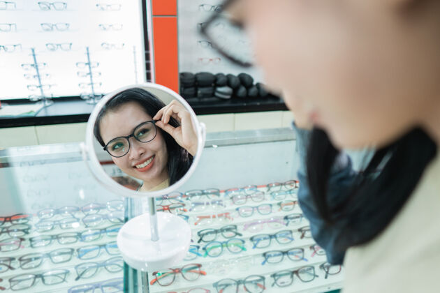 印尼一位美丽的女士戴着一副眼镜 这副眼镜是在眼科诊所挑选出来的 有一个眼镜展示窗的背景控股年轻人顾客