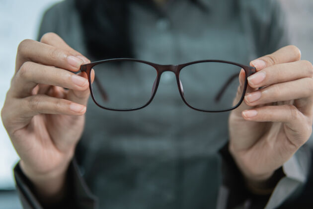 护理一个美丽的女人拿着一个眼镜样品在一个眼镜展示窗口的背景眼镜诊所眼镜师眼镜镜片