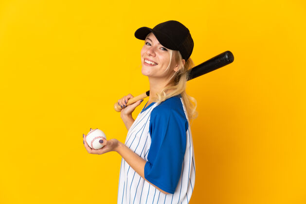 酷一个被隔离在黄色背景下打棒球的俄罗斯年轻女子玩棒球漂亮
