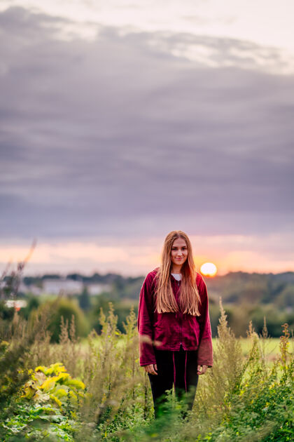 休闲美丽的白人女孩 棕色头发 在田野里摆着姿势 身后是鲜艳的夕阳色女性肖像太阳