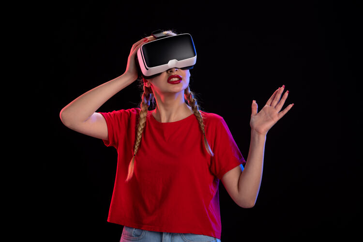 虚拟现实年轻女性在黑暗科技视觉超声上玩虚拟现实的前视图护目镜年轻女性视觉