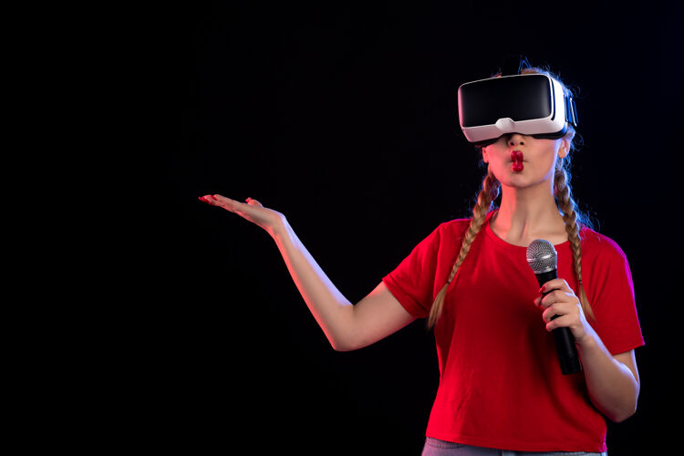 姿势年轻女性的肖像玩虚拟现实和唱歌与麦克风黑暗的视觉音乐游戏游戏虚拟现实视觉