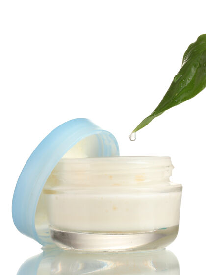 皮肤护理打开一个盛着鲜嫩绿叶的奶油的玻璃罐 滴在白色的水滴里丰富芳香疗法化妆品