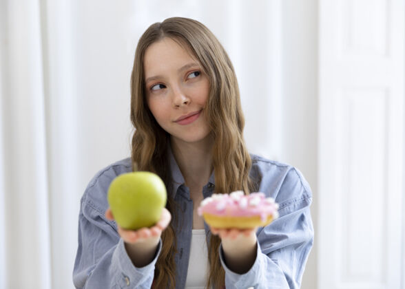 保健吃甜甜圈和苹果的女人模特饮食健康