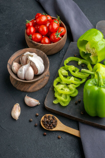 番茄全切切碎的青椒在木制砧板上的特写镜头西红柿在碗里大蒜素在黑色毛巾上的黑色表面甜椒毛巾切
