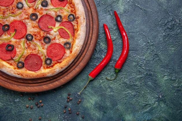 西红柿半张美味的比萨饼放在木制砧板上 红辣椒放在独立的黑色表面上 有足够的空间削减美味比萨饼一半