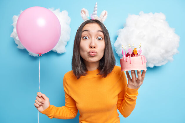 模型女人撅着嘴享受节日活动捧着美味蛋糕和充气气球庆祝26岁生日许下愿望奇迹个人氦