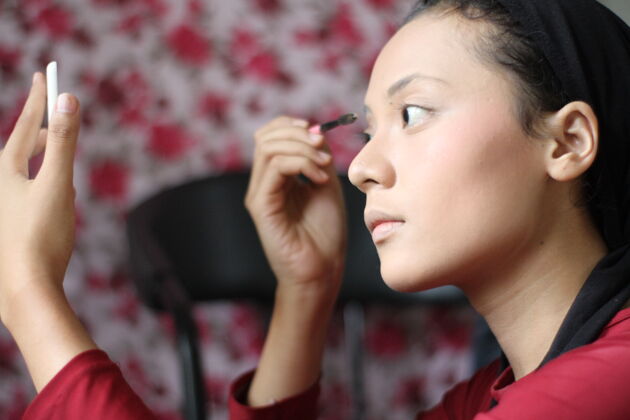民族用刷子和镜子化妆的年轻女人头亚洲质地