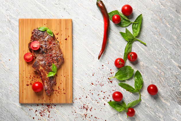 食物美味的烤牛排配番茄和罗勒 放在浅色桌上热肉自然