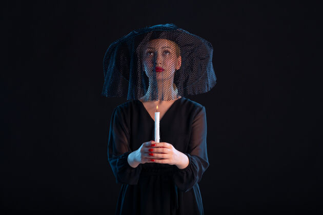 服装悲哀的黑衣女手持蜡烛对黑死病的葬礼悲伤死亡表演蜡烛
