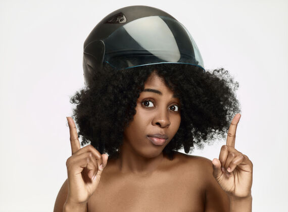 面部在白色工作室背景上 一位穿着摩托车头盔的美籍非洲妇女的肖像美丽和皮肤保护的概念奶油极端骑