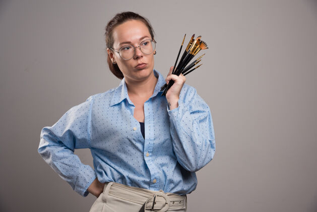 手女艺术家拿着画笔在灰色高质量的照片艺术家画家女性