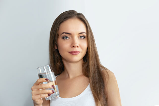口渴健康的生活方式年轻喝一杯新鲜水的女人水 保健品 饮料.手持透明玻璃的快乐微笑女模特的肖像年轻水合饮食