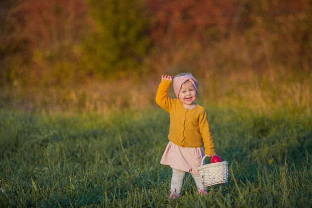 美丽可爱的小女孩走在秋天的花园里 手里拿着一个红色的篮子apples.portrait一个快乐的女孩在明媚的秋天clothes.warm明媚的秋天孩子帽子树叶