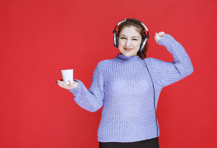 年轻人戴着耳机的女孩喝着咖啡 感觉很有力量人类年轻Dj