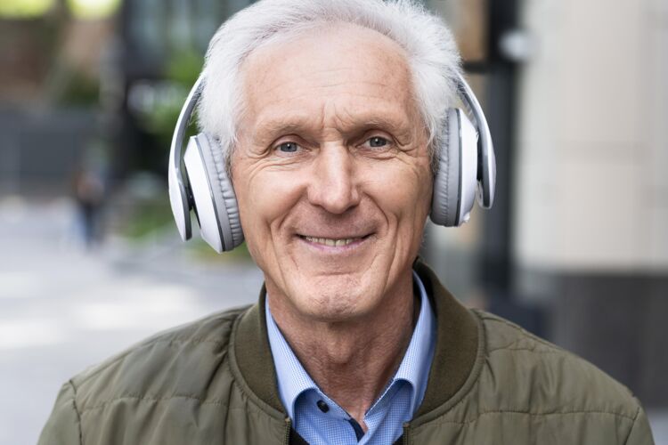 户外笑眯眯的城里老人戴着耳机听音乐城市老年人老年人