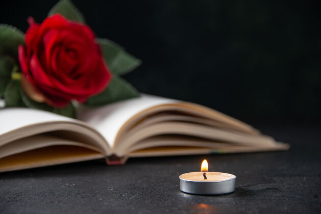 蜡烛在黑暗中打开书本看到红花的前视图开放庆典火