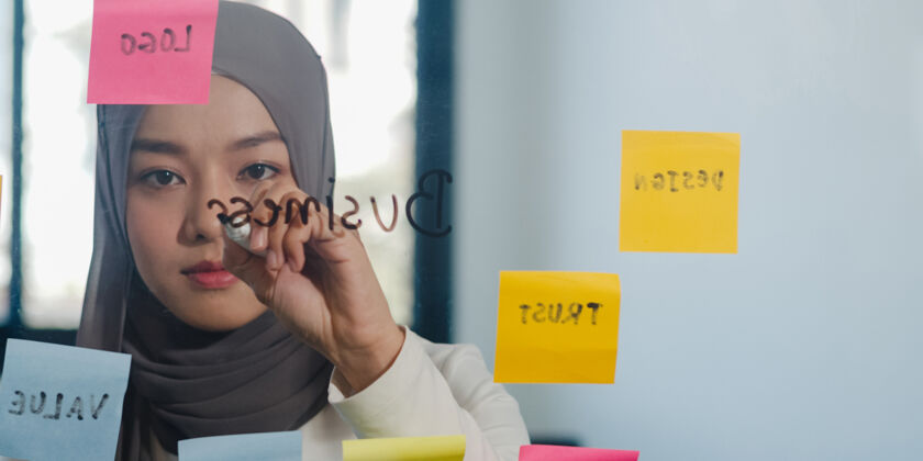 写作亚洲女士在新常态办公室的玻璃板上写信息 策略 提醒年轻马来西亚办公室