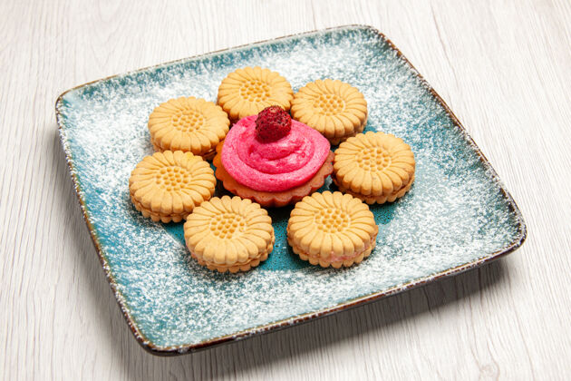 烘焙正面图：白色桌子上盘子里有水果蛋糕的小甜饼甜饼饼干蛋糕糖茶甜点水果饼干