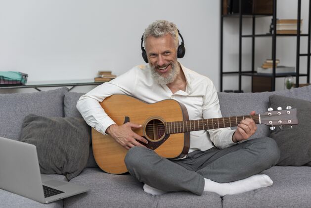老人老人在家的沙发上用笔记本电脑学习吉他课学习沙发沙发