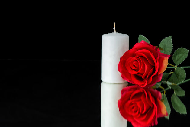 红黑上有红玫瑰的白蜡烛的正视图蜡烛黑花
