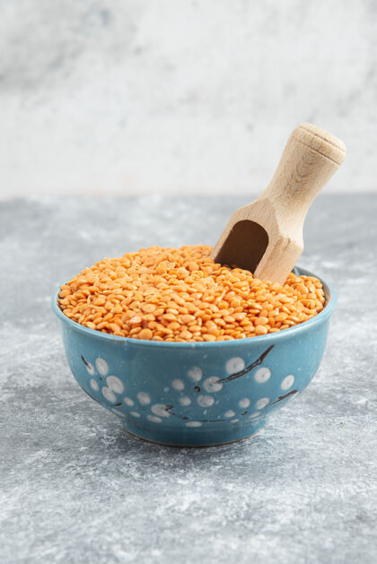 碗用勺子在大理石桌上放一碗生的红扁豆食物谷物木头