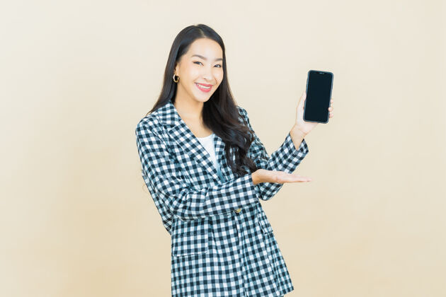 网络肖像美丽的亚洲年轻女子微笑着智能手机米色显示应用程序亚洲人