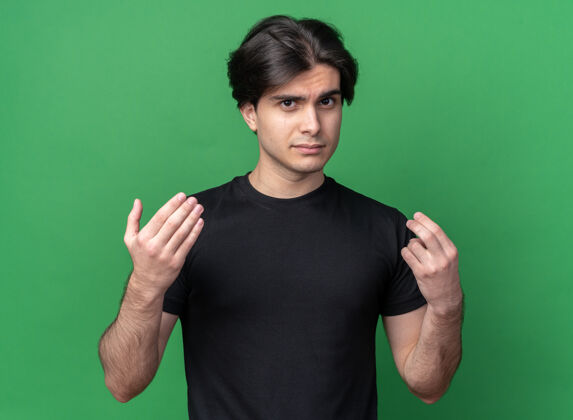 衣服悲伤的年轻帅哥 穿着黑色t恤 在绿色的墙上显示着孤立的提示手势表演感情姿势
