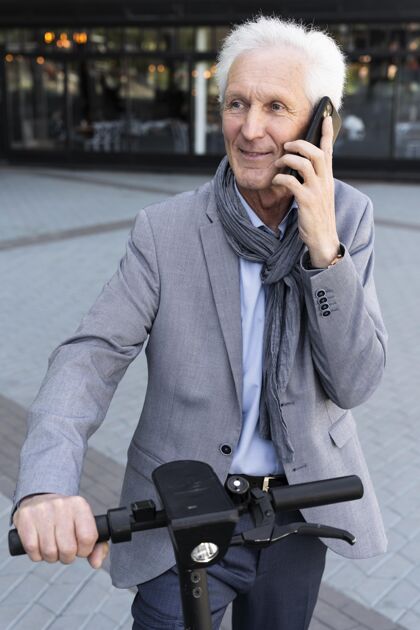 电动滑板车城里的老人在用智能手机说话户外讲电话老年人