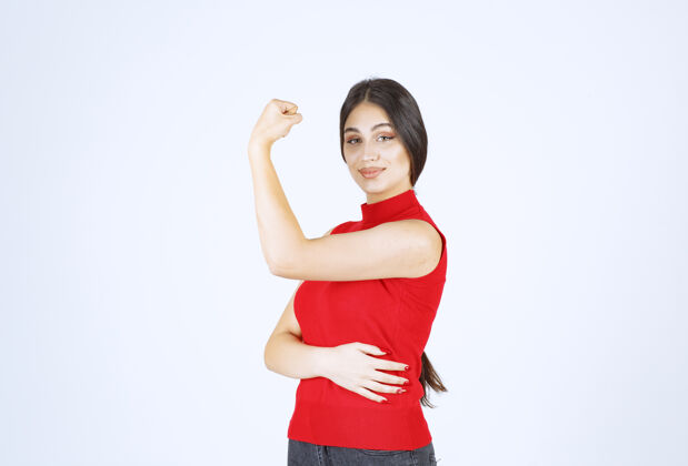 模特穿红衬衫的女孩展示她的拳头和力量姿势成人休闲