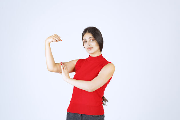 女人穿红衬衫的女孩展示她的手臂肌肉和拳头强壮年轻人