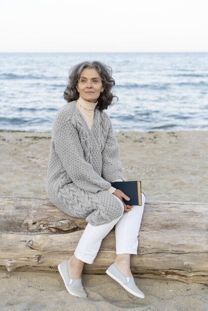 肖像海滩上的老太太拿着一本书户外女人垂直