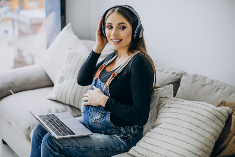 怀孕孕妇戴着耳机听音乐上网产前互联网人