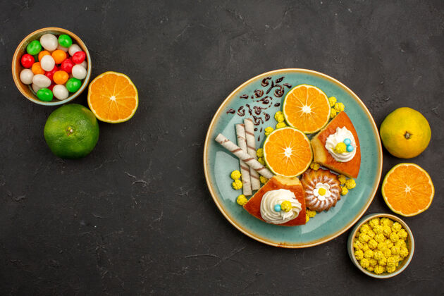 盘子俯瞰美味的派片与烟斗饼干和新鲜的橘子片在黑暗的桌子上水果蛋糕派甜饼干柠檬饼干派