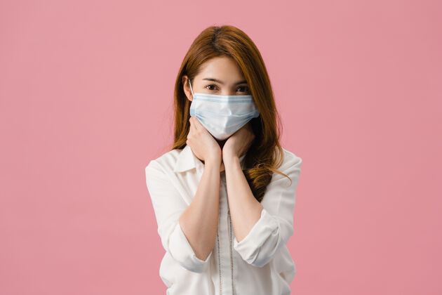 恐惧年轻的亚洲女孩戴着医用面罩 厌倦了压力和紧张 自信地看着隔离在粉色背景上的相机严重压力防护