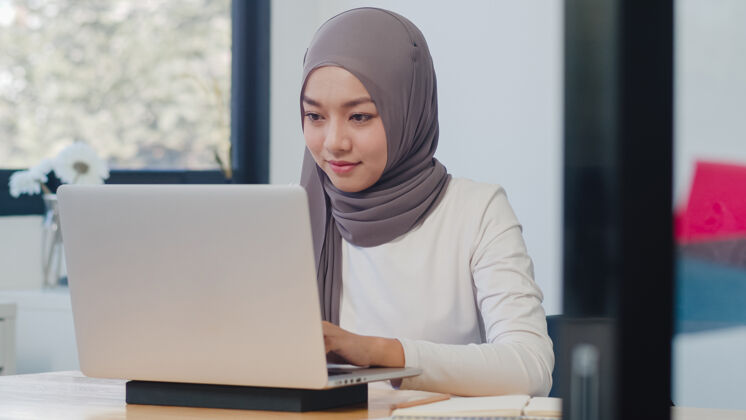 人美丽的亚洲穆斯林女士休闲装 在现代新常态办公室使用笔记本电脑工作雇员宗教大学